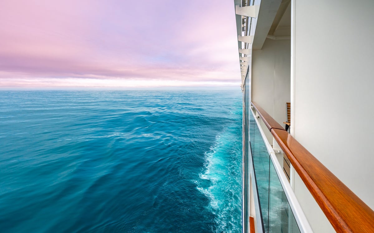 Cruise ship sailing toward a pink sunset horizon